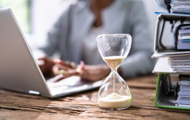 a person working at a desk next to a sand timer